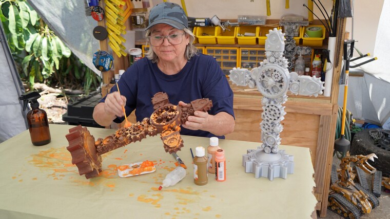Liza Trainer hand-painting a gear cross at her workbench in Hollywood, Florida