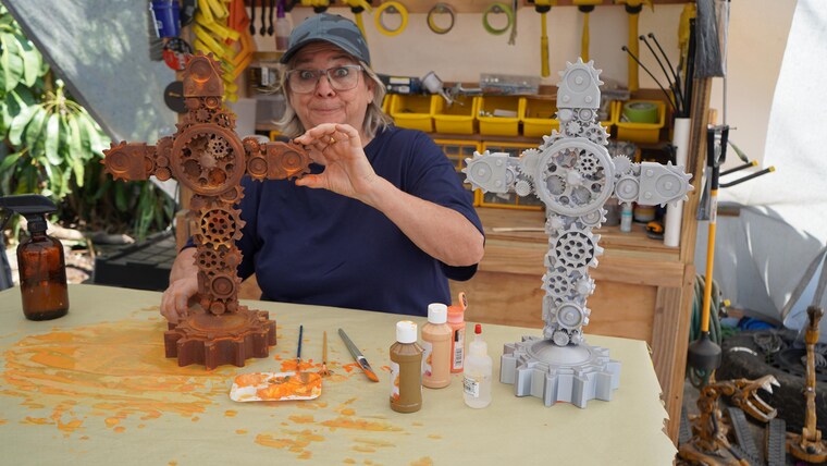 Liza Trainer holding a finished and an unpainted gear cross
